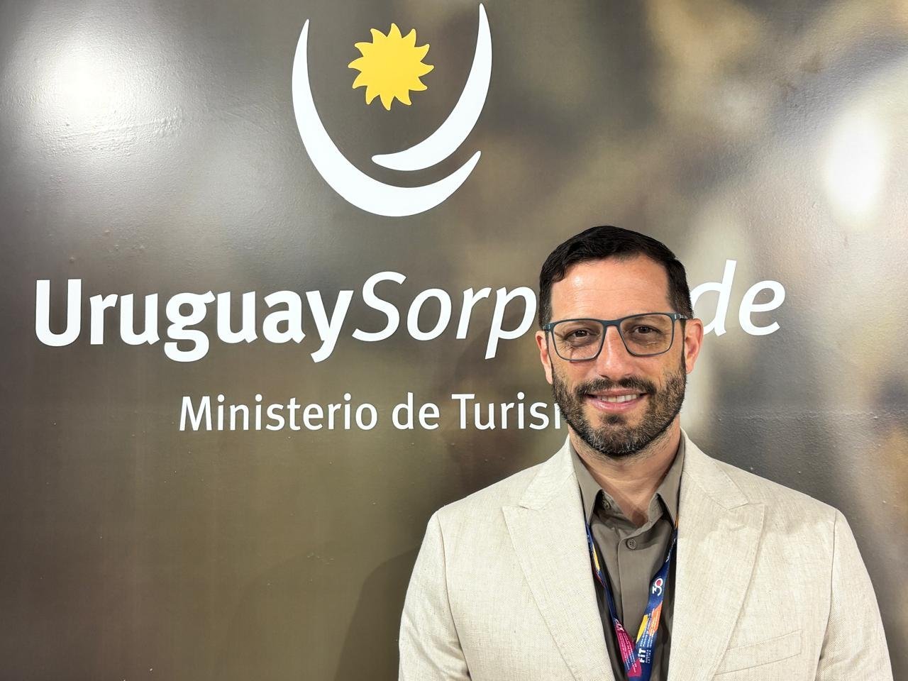 Cristian Pos, director nacional de Turismo de Uruguay, frente al logo del Ministerio de Turismo